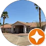 Single-story building with a tan roof, palm trees, and a clear blue sky, seen from a paved driveway—an inviting spot often praised in testimonials for its welcoming atmosphere.